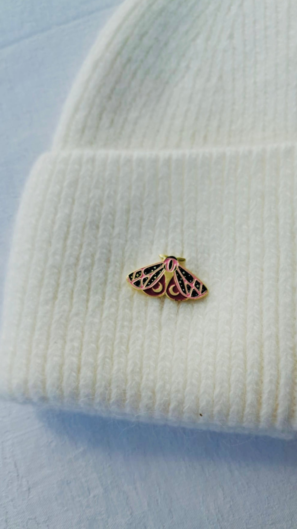 An ivory white knit angora beanie with a decorative butterfly brooch on the side
