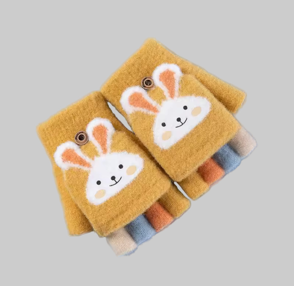 Pair of mustard yellow bunny-themed wrist warmers on a light blue background