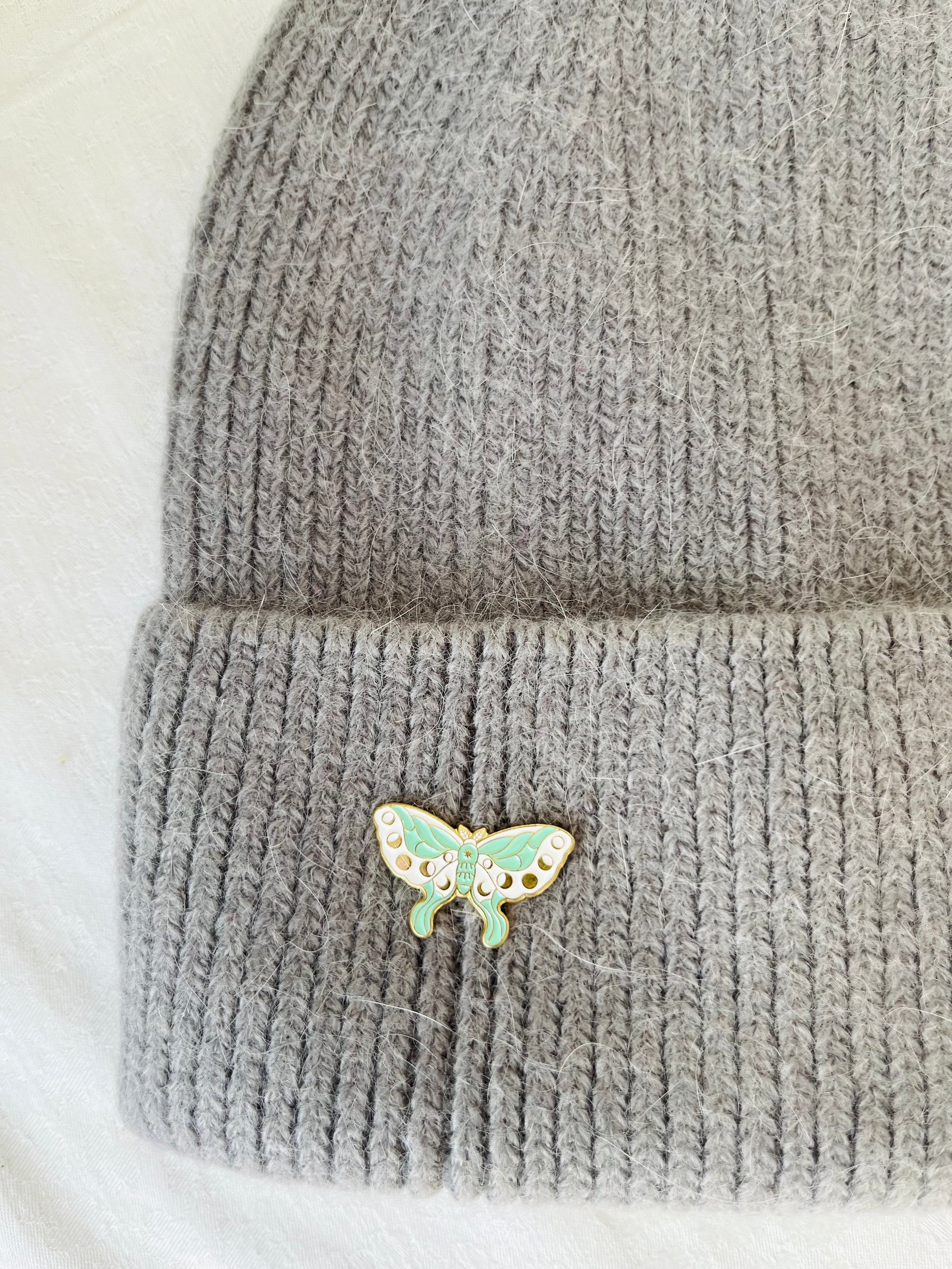 Gray knit angora beanie with a butterfly-shaped brooch for winter days