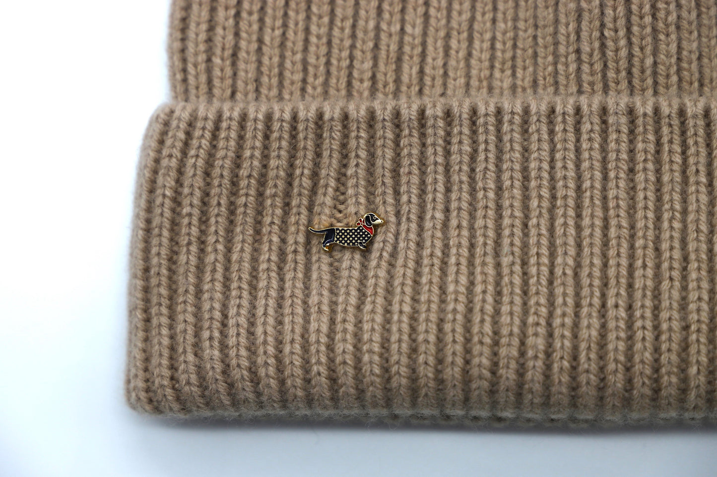 This Hat is a finest hat with a classic silhouette from Villanelle. A luxurious accessory for women and for men made from the softest natural sheep wool for extreme comfort and warmth. It is made in a trendy caramel beige color accompanied by an elegant dog pin. This product is sourced and manufactured in Poland.