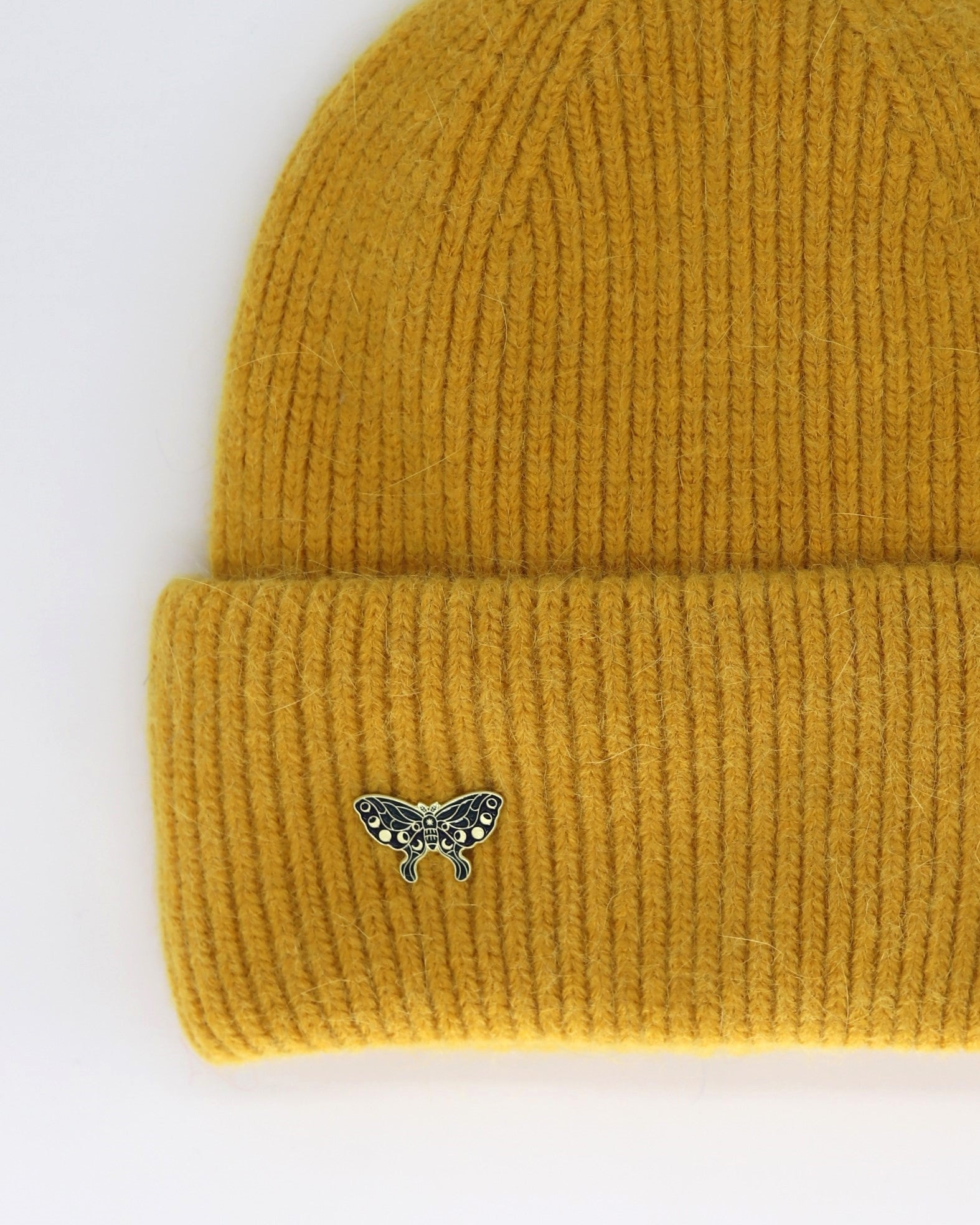 This Hat is a finest hat with a classic silhouette from Villanelle. A luxurious accessory for women made from the softest natural angora and sheep wool for extreme comfort and warmth. It is made in a trendy mustard yellow color accompanied by an elegant pin. This product is sourced and manufactured in Poland.