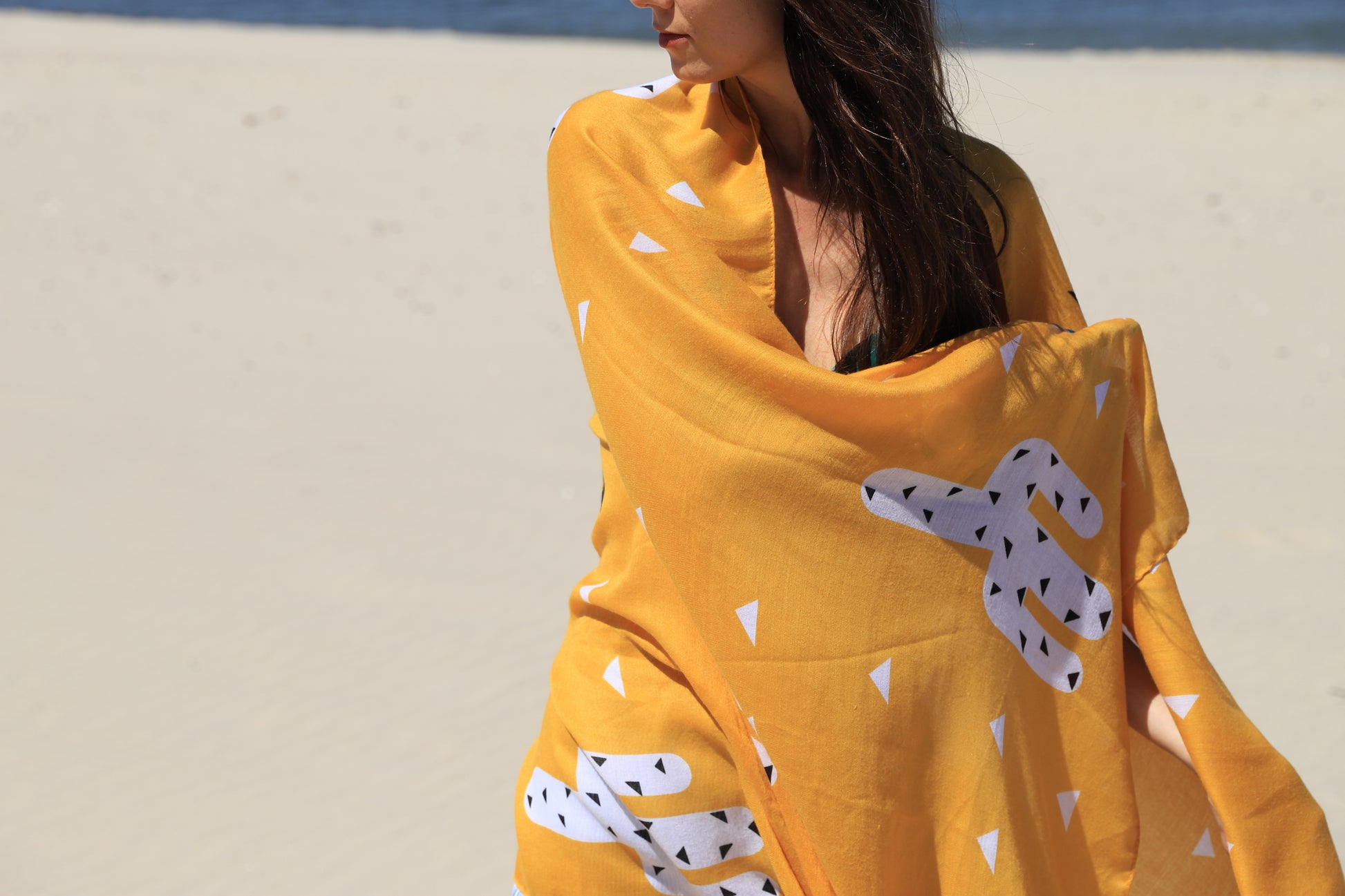 This is a soft XL-size viscose beach pareo and scarf for women with trendy tassels in modern geometric and cacatus prints in yellow to give you a happy, fresh and modern look. This sustainable and vegan PETA certified pareo is made from sustainably sourced viscose. This versatile pareo can be used as a skirt, dress, scarf or shawl.
