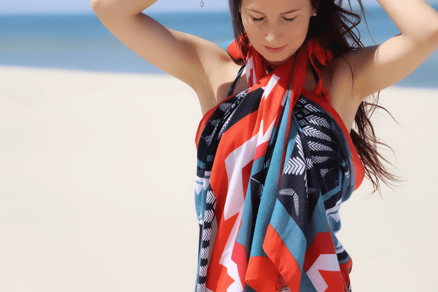 This is a soft XL-size viscose beach pareo and scarf for women with trendy tassels in modern geometric prints in black, turquoise and red to give you a happy, fresh and modern look. This is a sustainable and vegan PETA certified pareo made from sustainably sourced viscose. This versatile pareo can be used as a skirt, dress, scarf or shawl.